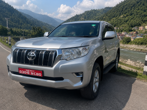 Luxury Toyota Land Cruiser Prado driving through Nepal's scenic mountain highway between Kathmandu and Pokhara
